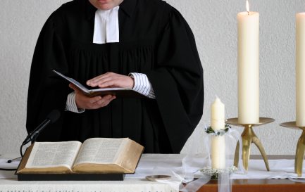 Un pasteur en robe lors d’une célébration. / ©iStock / Freder 